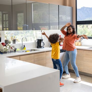Mother and child dancing happily in the kitchen.