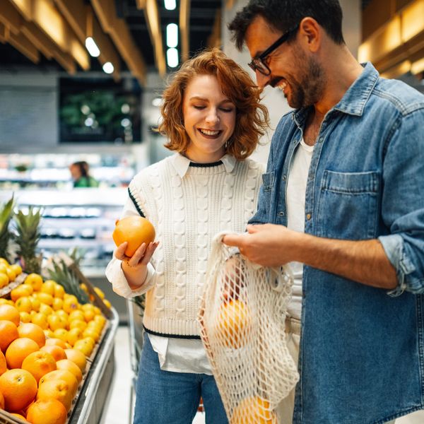 Couple happily shopping for oranges at a grocery store.
