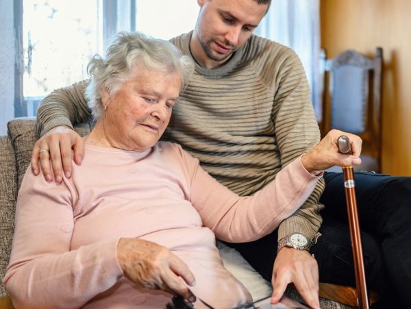 Elderly woman and younger man sharing a moment with a tablet.