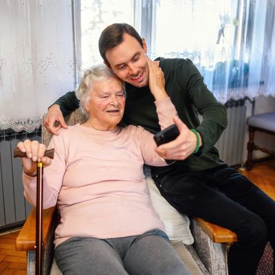 Young man and elderly woman taking a selfie together at home.