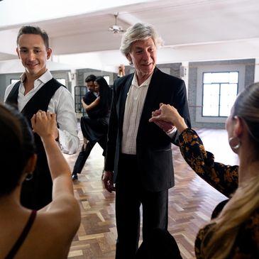 Dance instructor guiding couples in a spacious studio.