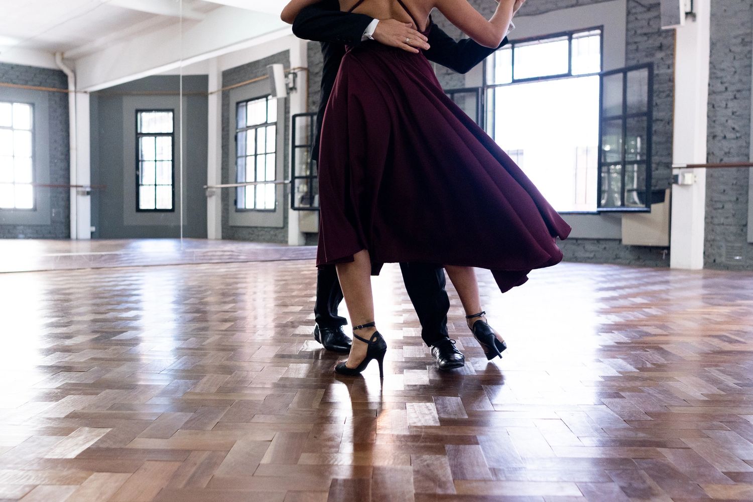 Couple dancing gracefully in a spacious, sunlit studio.