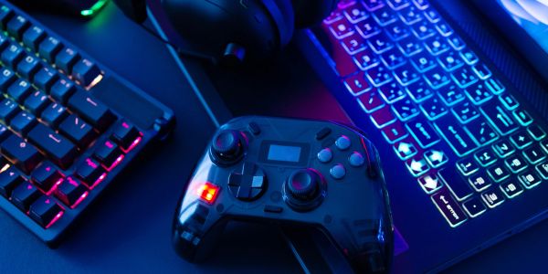 Gaming controller and RGB keyboards in blue lighting.