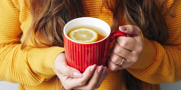 Person holding a red mug with lemon tea.