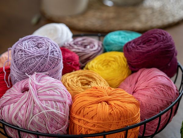 A basket filled with multicolored yarn balls.