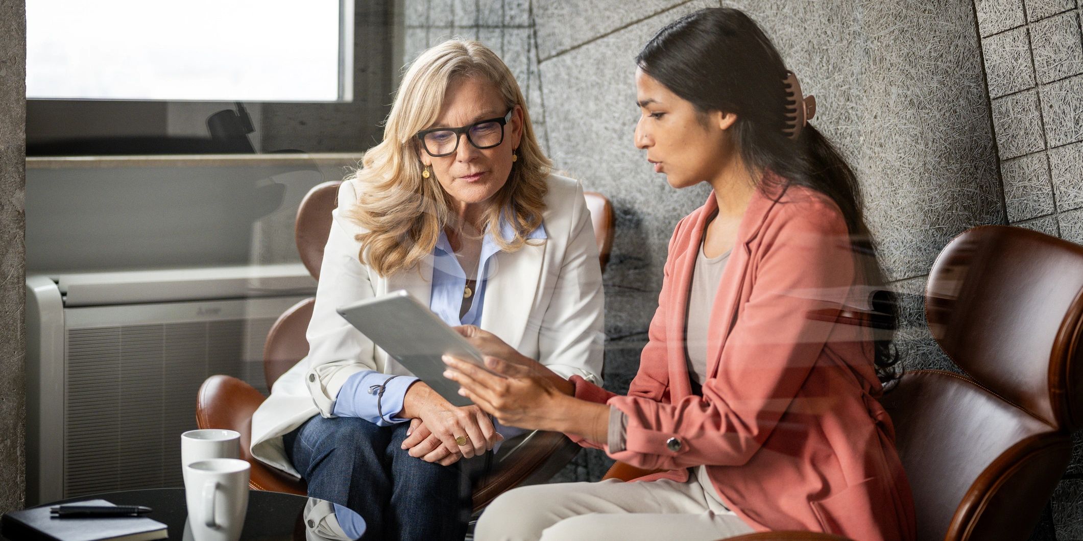 Two women discussing something on a tablet.