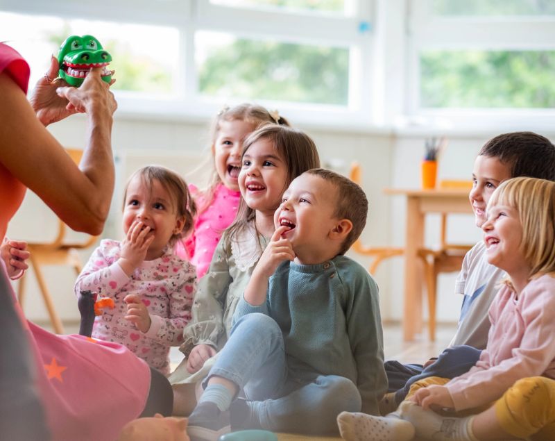 the teacher entertains the children in the kindergarten, the children are happy and enjoying themselves
