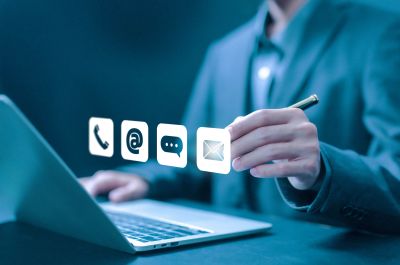 Person in suit using digital communication icons over laptop.
