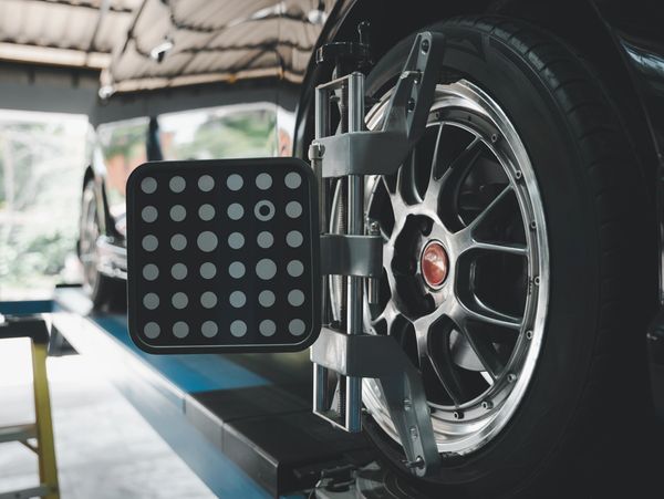 Car wheel alignment device attached to a tire in a garage.
