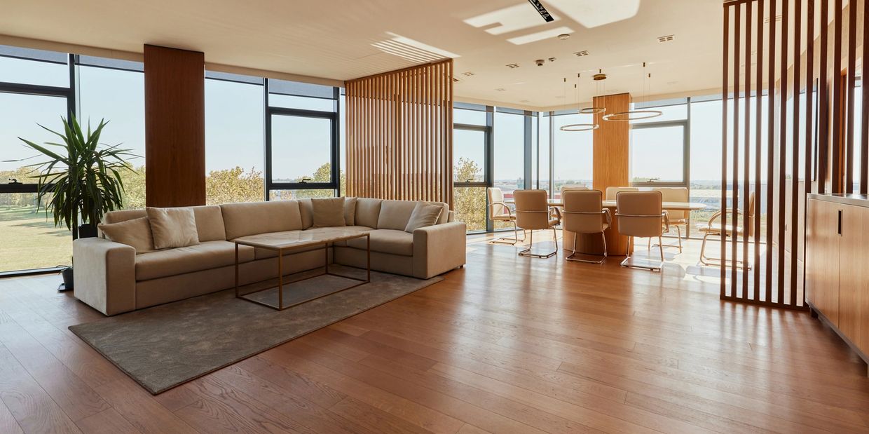 Modern open-plan living and dining room with large windows and wood floors.