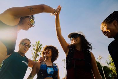 Group of runners in a circle. One runner is giving a high five to another runner.