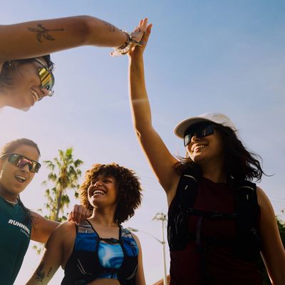 Group of friends enjoying a high-five outdoors under a clear sky.