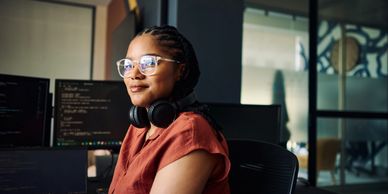 Woman with headphones working at a computer.