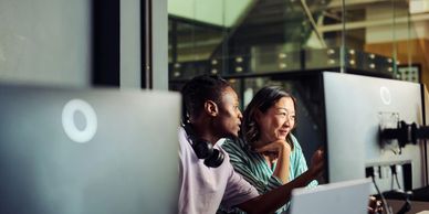 Two colleagues collaborate in front of a computer in a modern office.