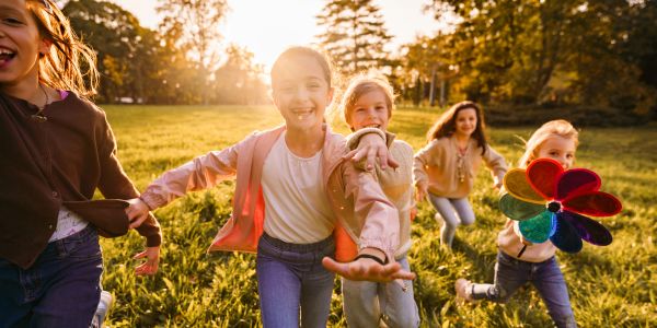 Children running and playing with a colorful pinwheel outdoors.
