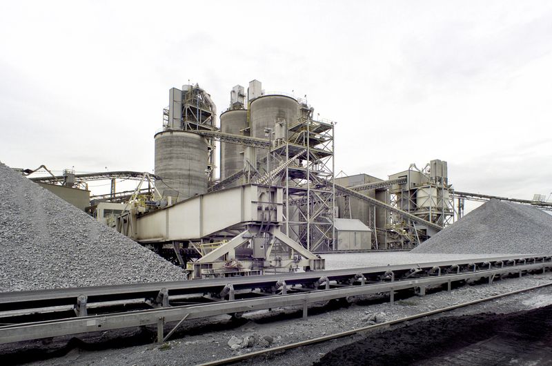 The raw materials handling area of a cemment factory where local limestone is quarried, ground, and mixed with clay, aluminum, gypsum, and small amounts of other minerals, then baked in a kiln to make clinker.  The clinker is then ground to make a fine cement powder that when mixed with water rock and sand, cures to a rock hard construction material.