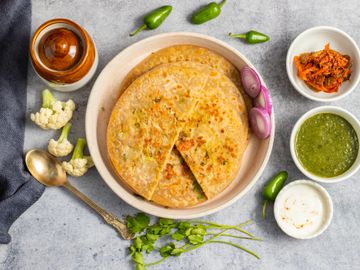 Plate of stuffed Indian parathas with chutney, yogurt, and pickles.