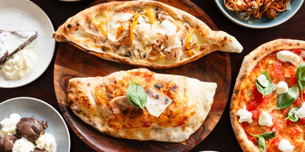 Variety of Italian pizza and dessert dishes on a table.