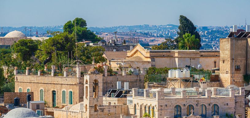Cityscape with historic stone buildings and greenery.