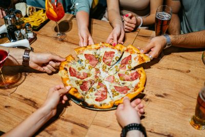 People sharing a pepperoni pizza at a wooden table.