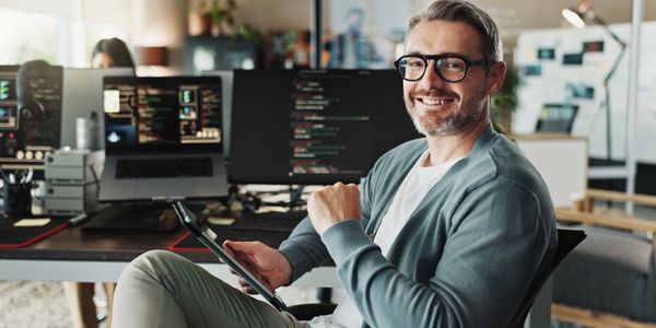 Smiling programmer with tablet in modern office environment.