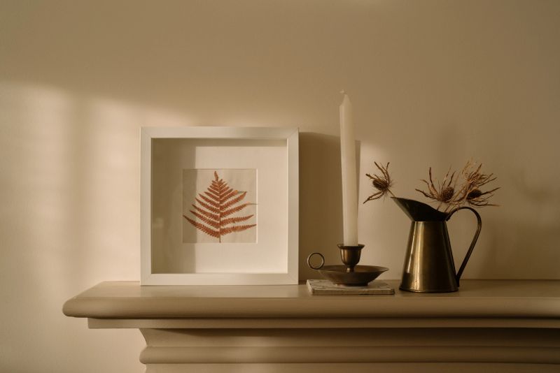 Elegant composition of cozy living room interior with fireplace, vintage french vase with flowers, candle and personal accessories. Home decor.
