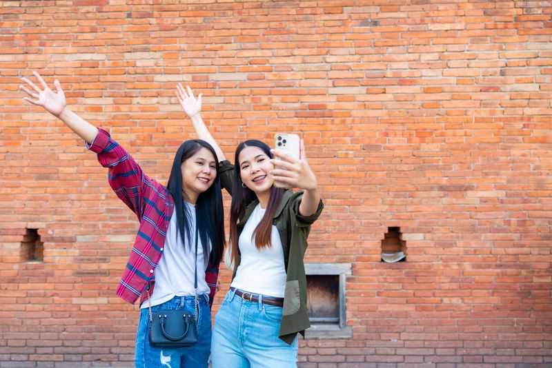Happy Asian woman using smartphone taking selfie or vlogging during travel and shopping traditional street market in Chiang Mai city. People enjoy outdoor lifestyle travel Thailand on holiday vacation
