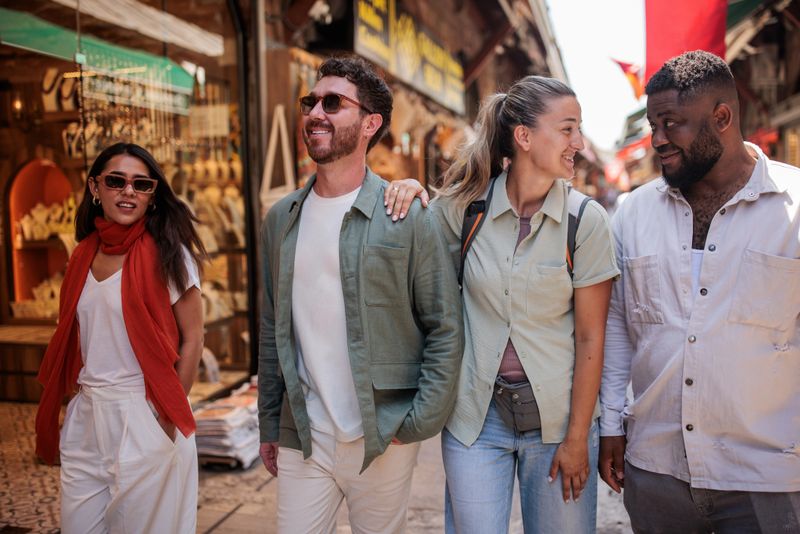Multiracial group of friends explore market street, engaging in conversation. The market is bustling with cultural significance and local goods on display in Istanbul, Turkey.