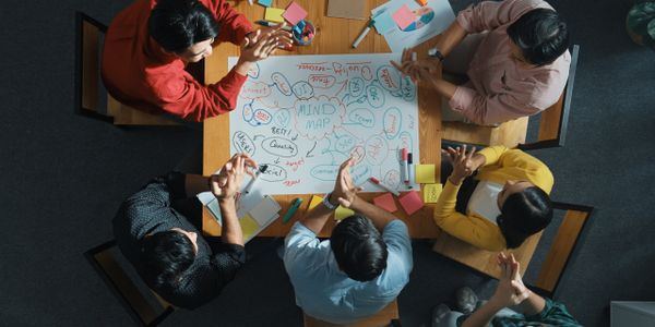 Team brainstorming session around a mind map on a wooden table.