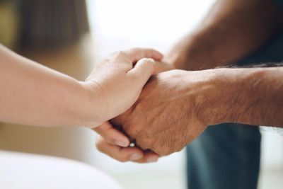 Two people holding hands in a comforting gesture.