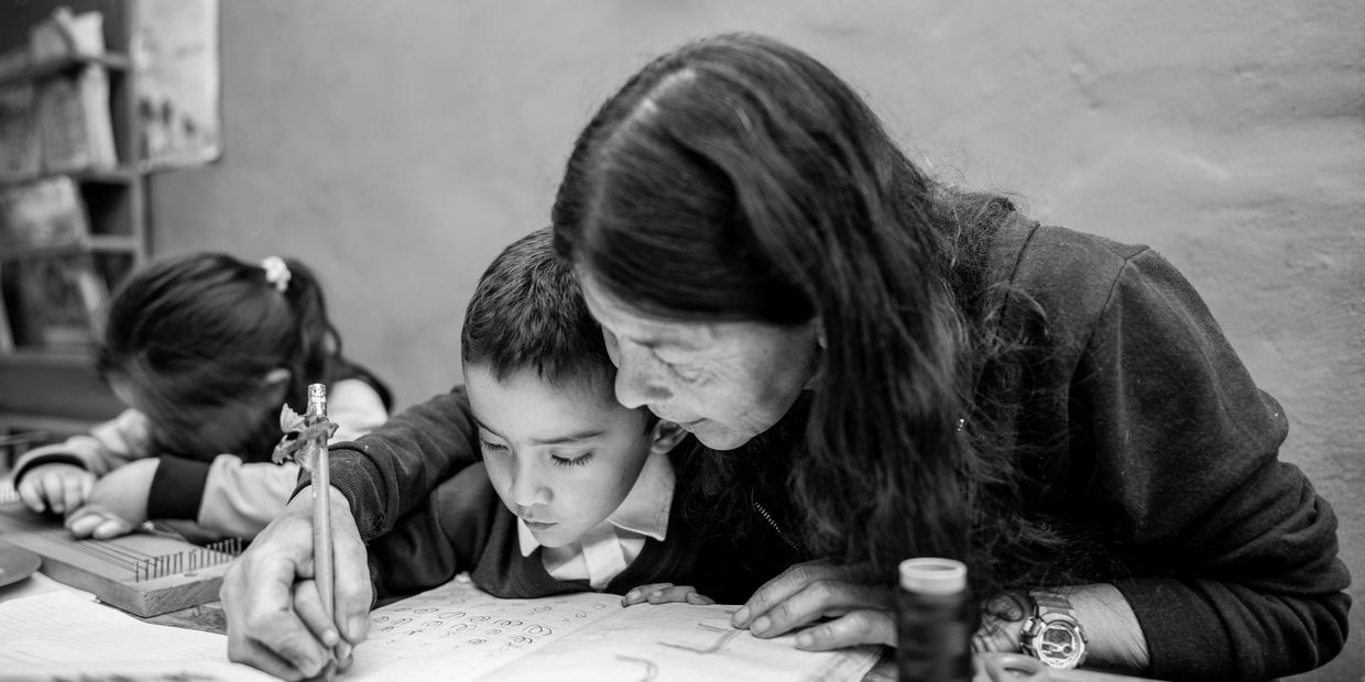 Teacher helping child write