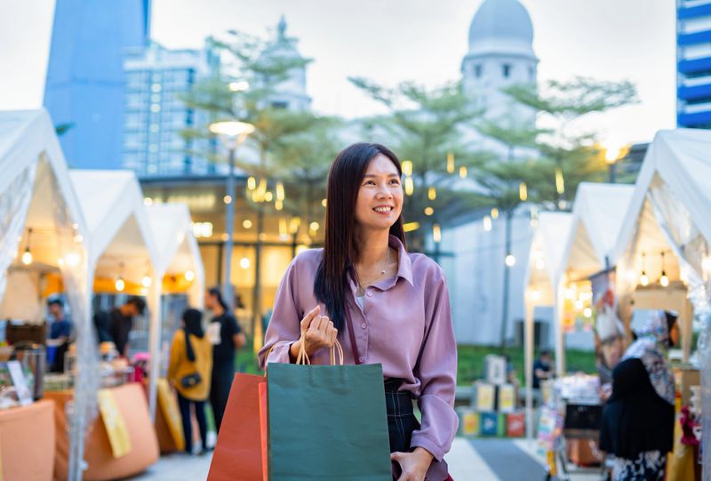 woman shopping goods at night market in kuala lumpur. enjoy purchasing with happiness