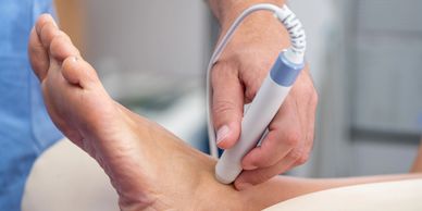 Close-up of a medical professional using an ultrasound device on a patient's ankle.