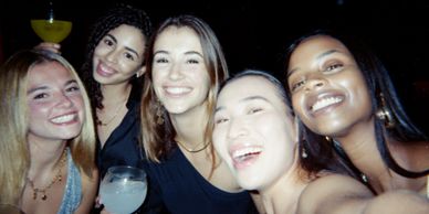 Group of five women smiling at a party.
