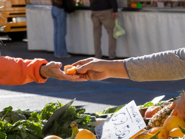 Hands exchanging produce at a market.