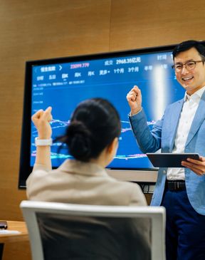 Business meeting with a man presenting financial data on a large screen.