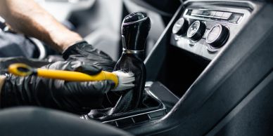 Person cleaning a car's gear shift with a brush.