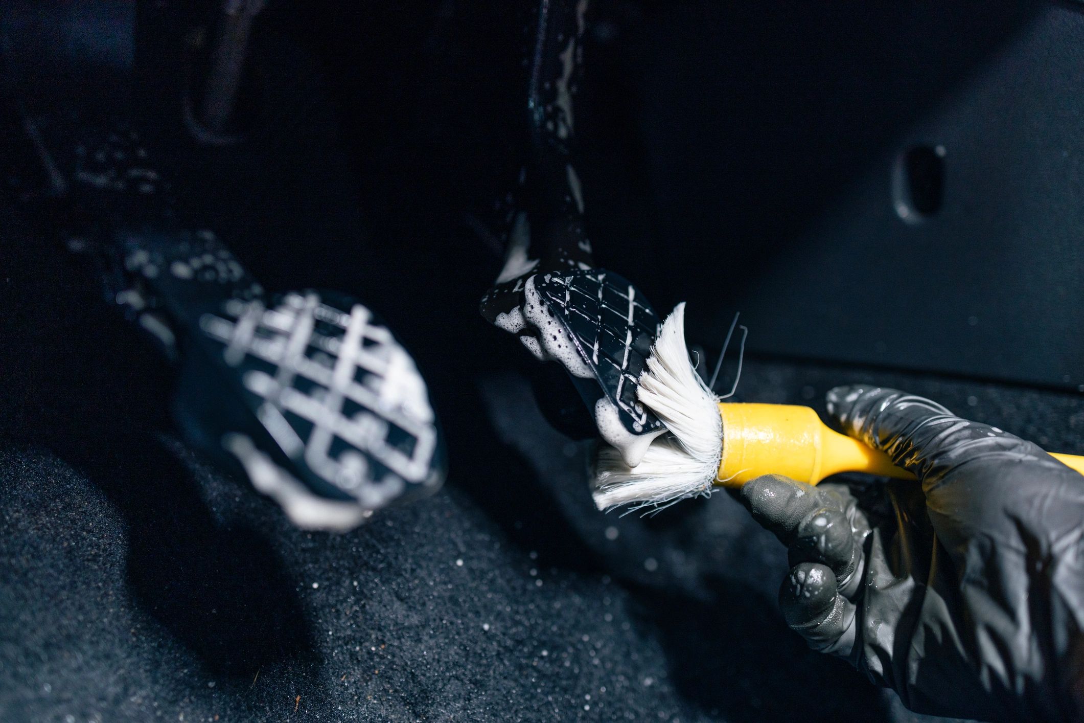 Cleaning car pedals with a brush and foam.