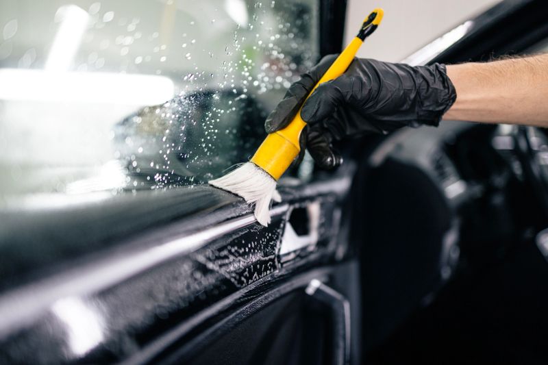 Professional car interior cleaning with the brush removing dust and dirt from the vehicle.