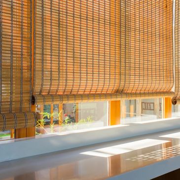 Sunlight filters through bamboo blinds onto a windowsill.