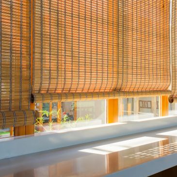 Sunlight filters through bamboo blinds onto a windowsill.