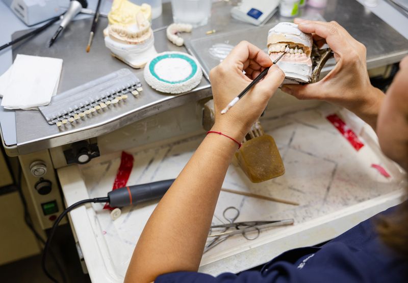 Detailed view of a dental technician restoring a dental mold at the workbench.