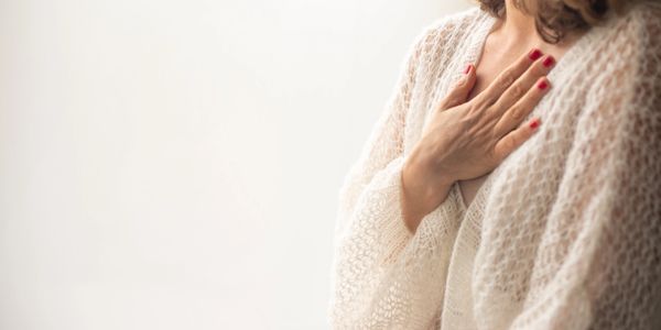 Woman with hand on chest wearing a cozy knitted sweater.