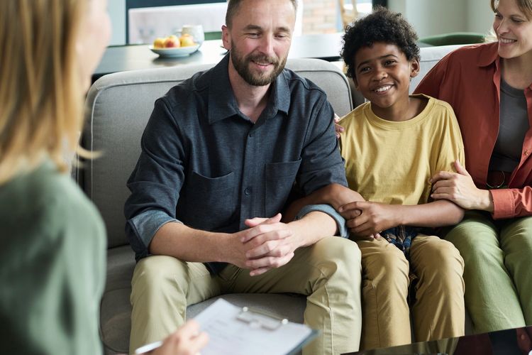 A happy family sitting on a couch during a counseling session.