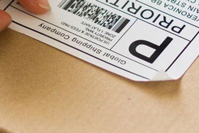 Warehouse worker packing and labeling a window tint film order for shipping