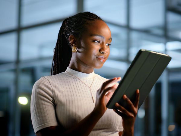 Young woman using a tablet with a focused expression indoors.