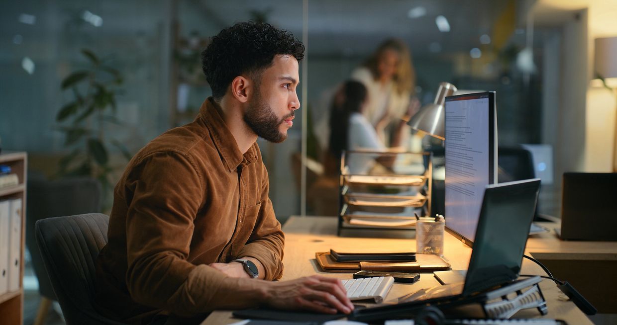 Man focused on work at dual monitors in a modern office.