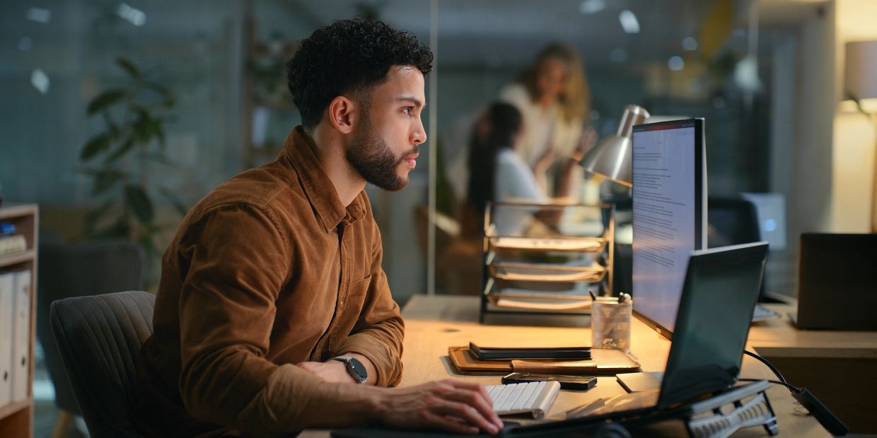 Man working focused on computer in office at night.