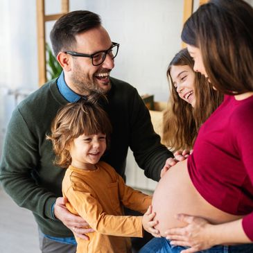 A happy family touching a pregnant woman's belly, sharing a joyful moment.