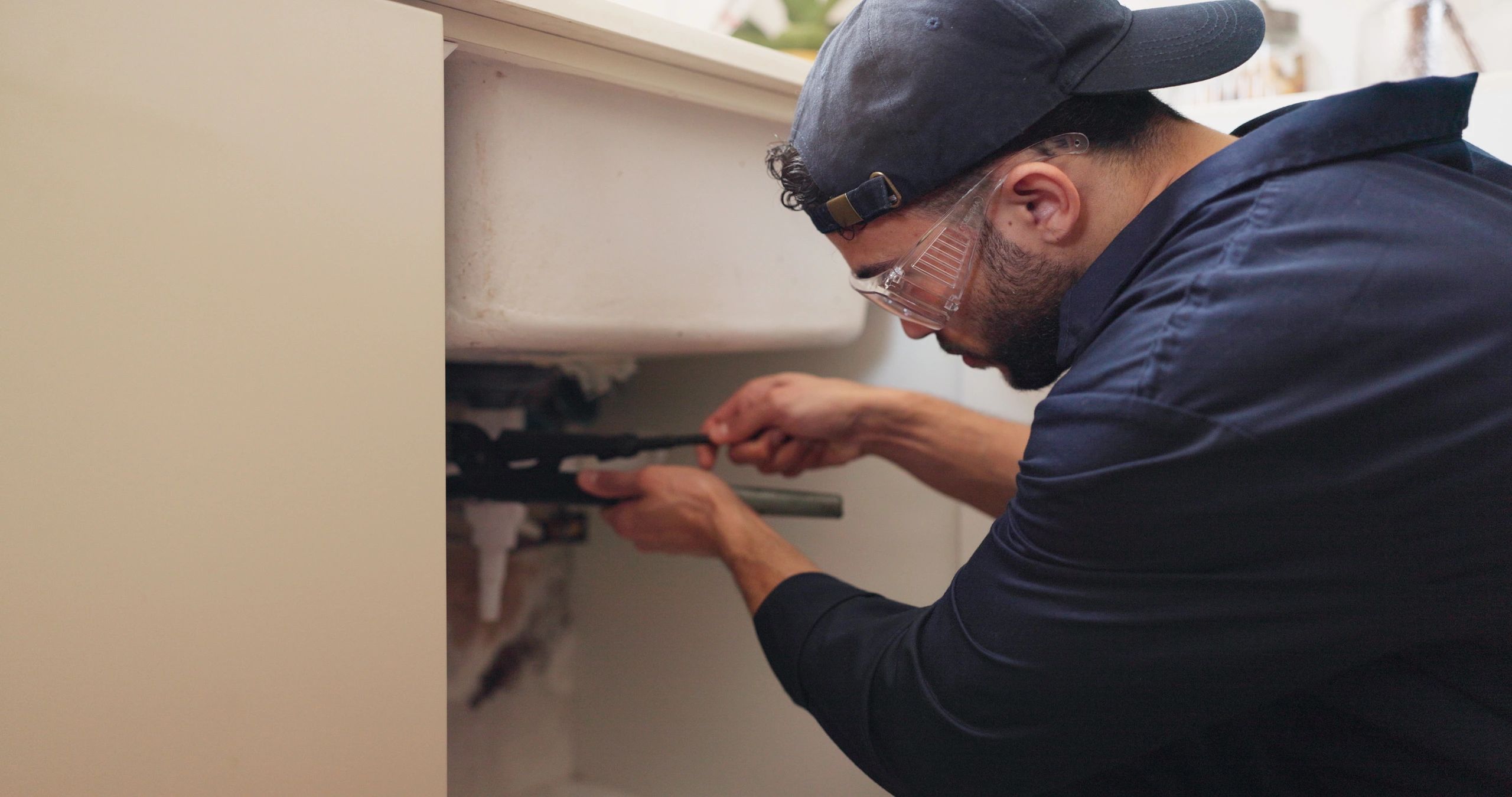 Man repairing plumbing under a sink.